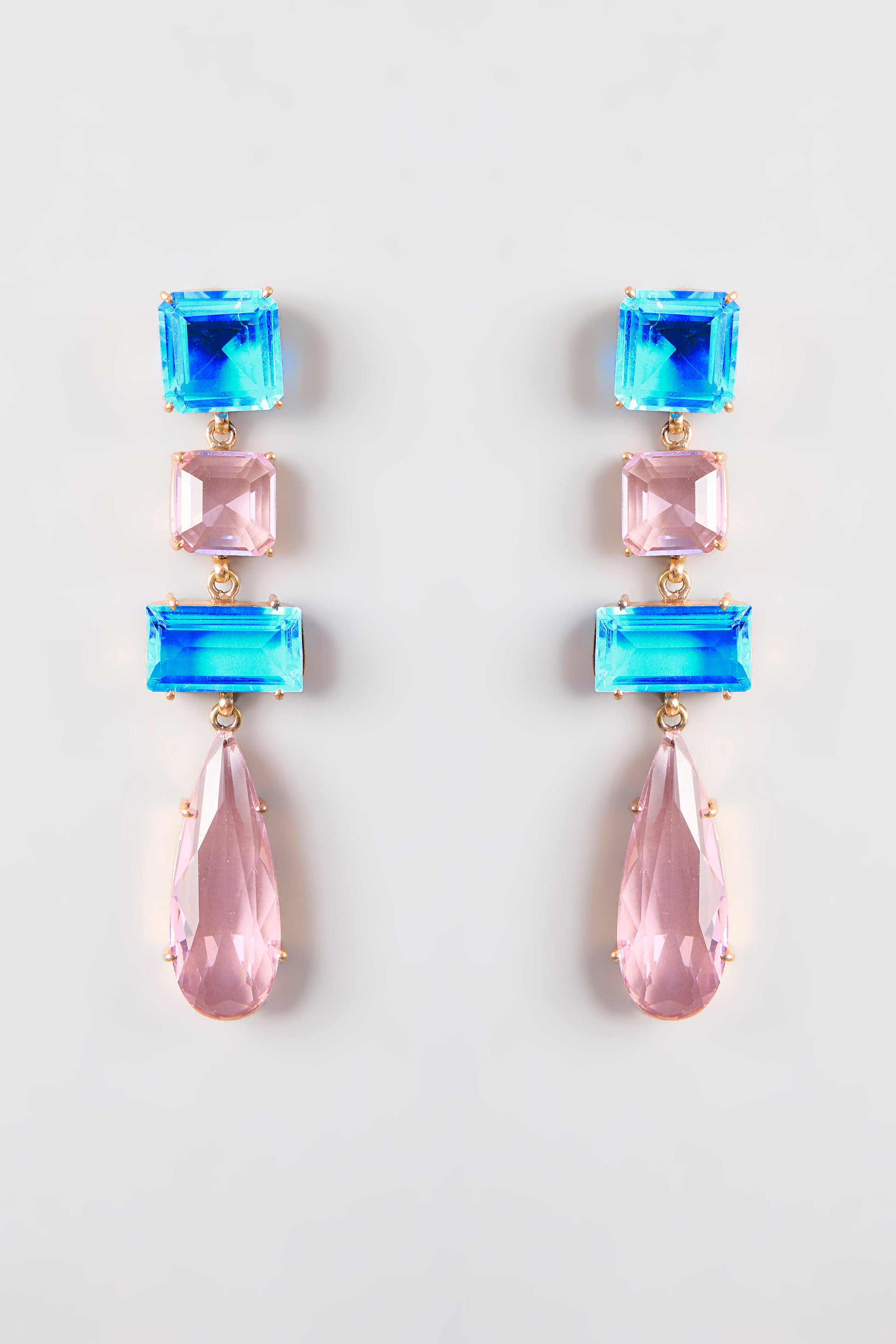 Close-up of Gleam Blue & Pink Drop Earrings, featuring ocean blue and blush pink crystals against a neutral background.