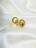 Pair of gold Roman crystal earrings displayed on a white satin background showcasing intricate detailing.