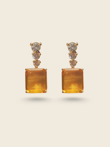 Elegant drop earrings featuring three sparkling round diamonds and a large rectangular amber gemstone set in gold.